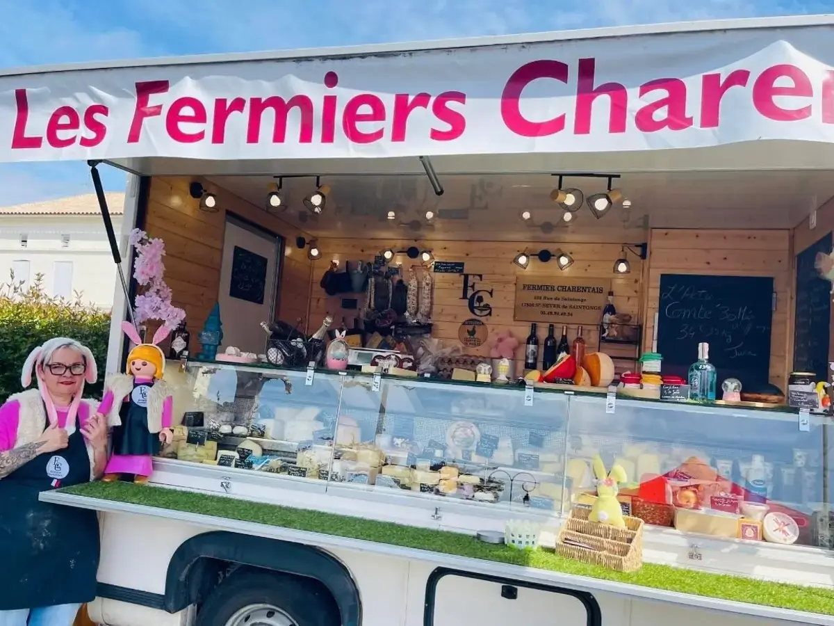 Le camion-boutique des Fermiers Charentais installé sur un marché, une vendeuse souriante devant l’étal réfrigéré.