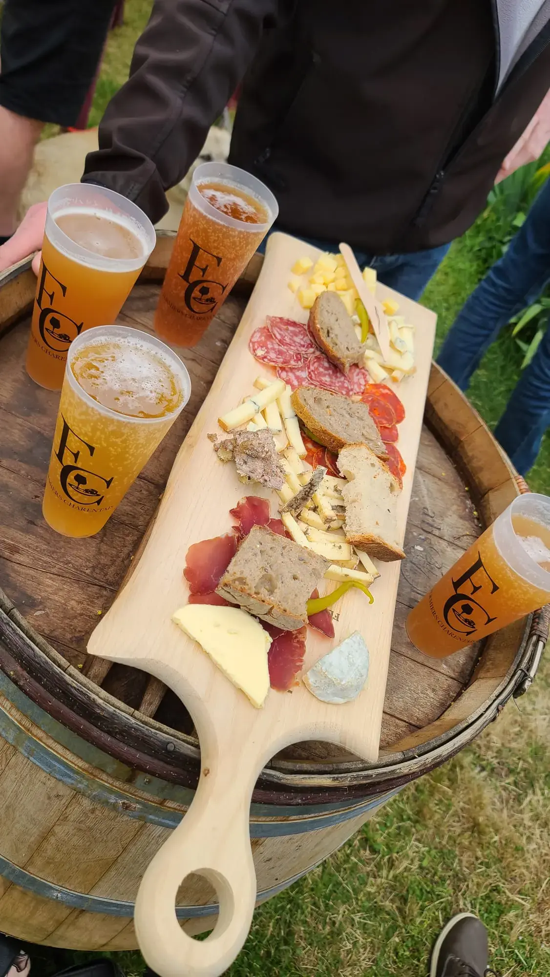 Une planche de charcuterie et de fromage posée sur un tonneau, avec des bières.