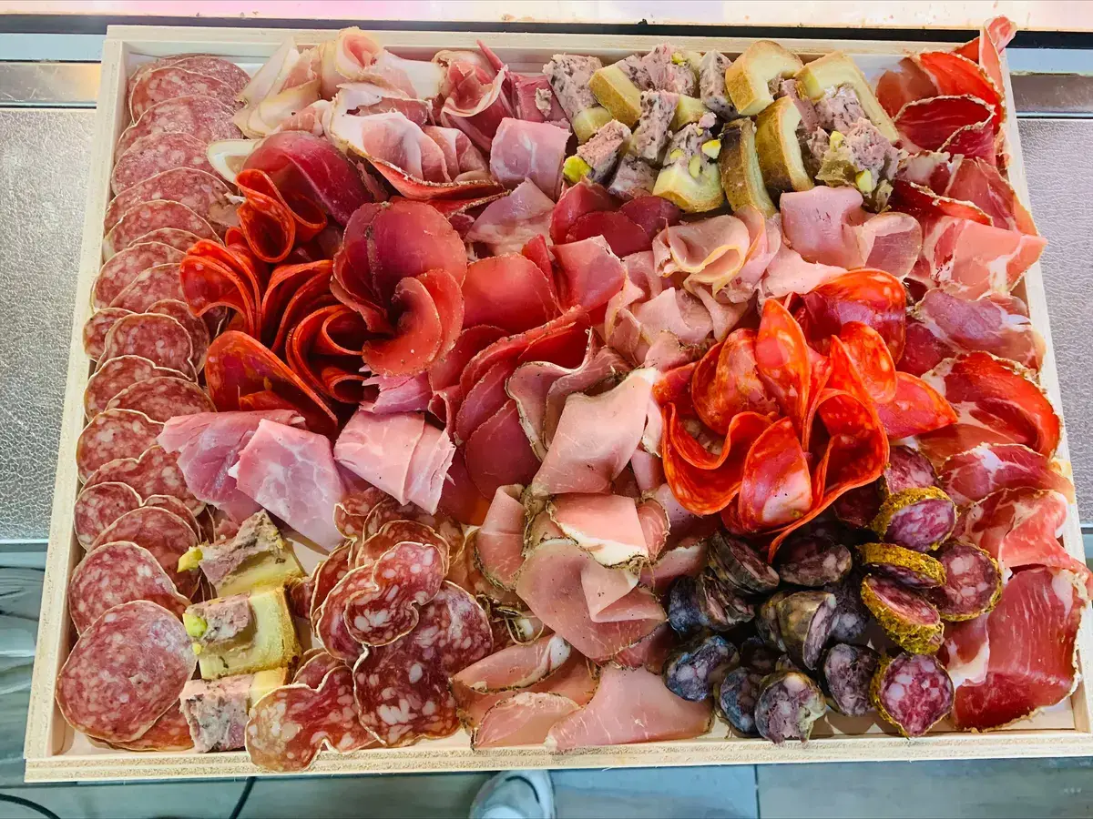 Un grand plateau de charcuteries : jambons, saucissons, terrines.
