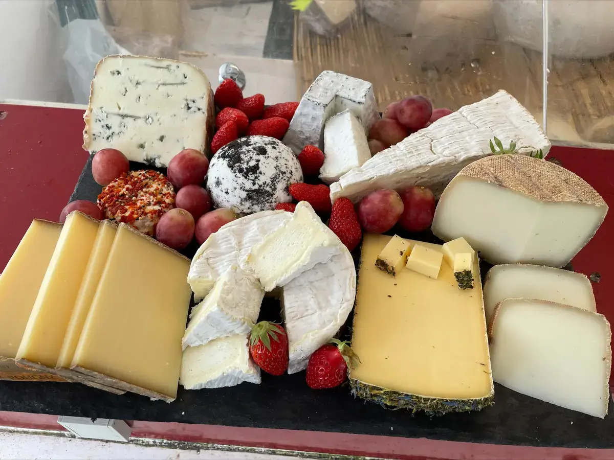 Un plateau de fromages affinés, avec des fraises et des raisins.