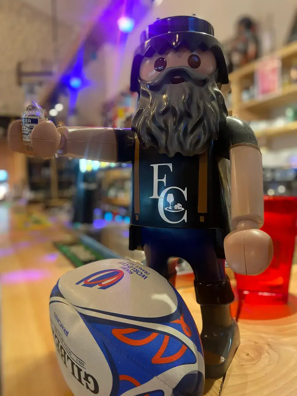 Un Playmobil géant barbu au maillot des Fermiers Charentais, ballon de rugby au pied.